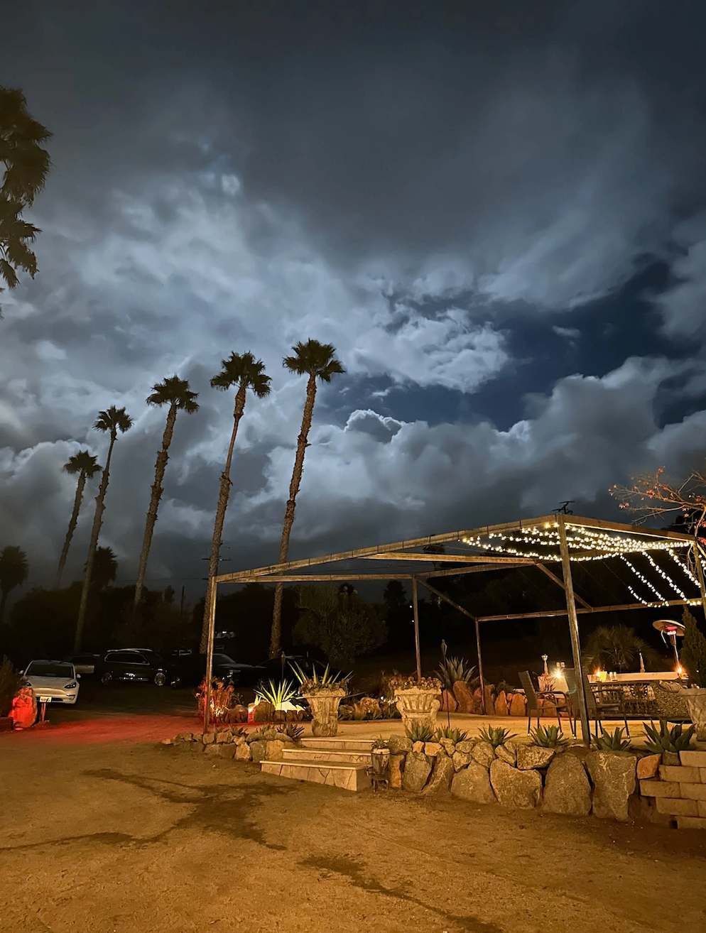 Evening view of the estate grounds under dramatic clouds and string lights