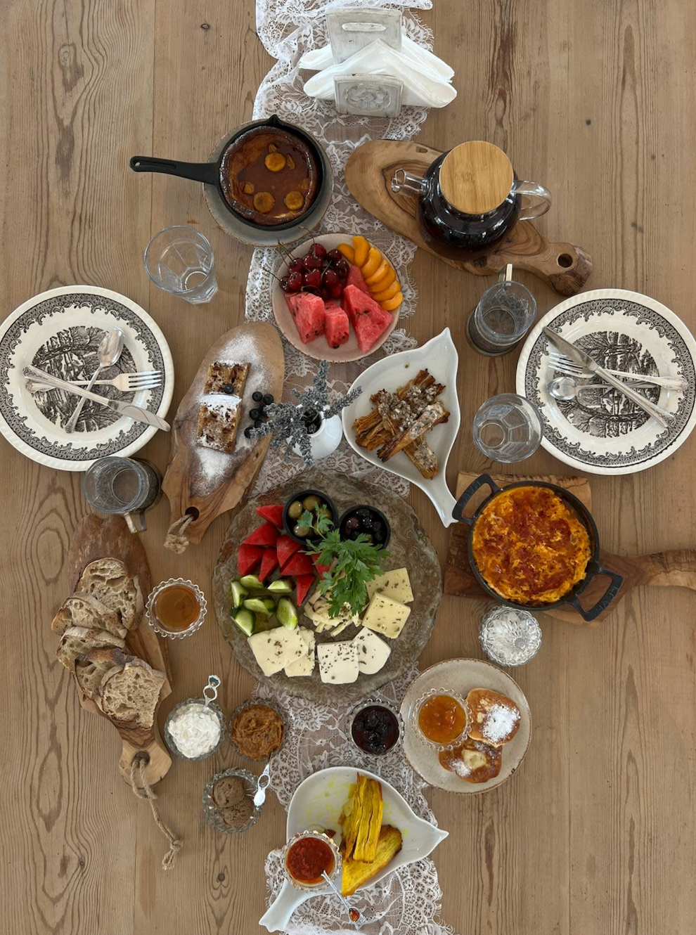 Mediterranean grazing table with cast-iron pots, fresh fruit, cheeses, and breads
