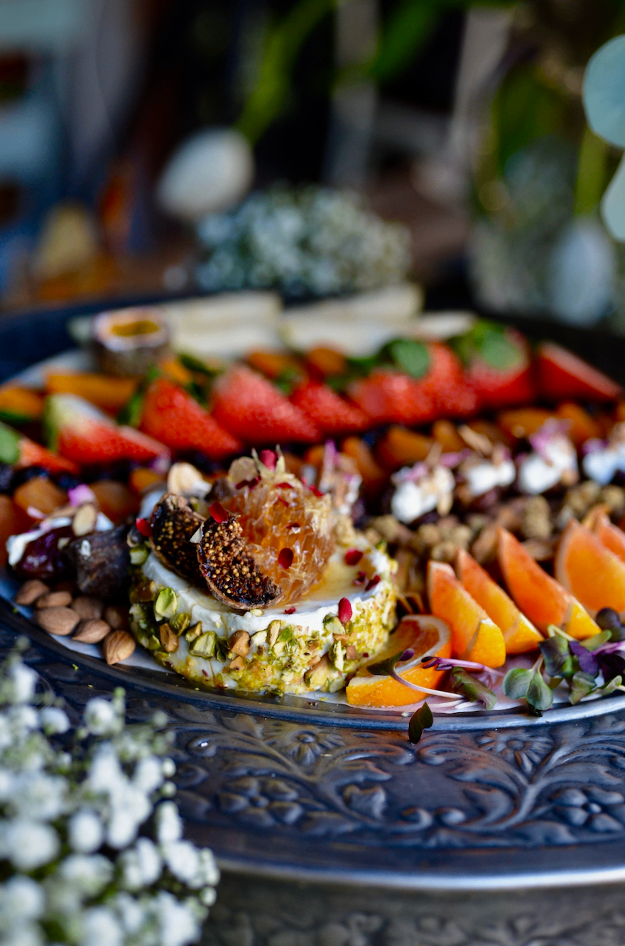 Pistachio-crusted labneh with figs, honeycomb, and seasonal fruit on an engraved platter